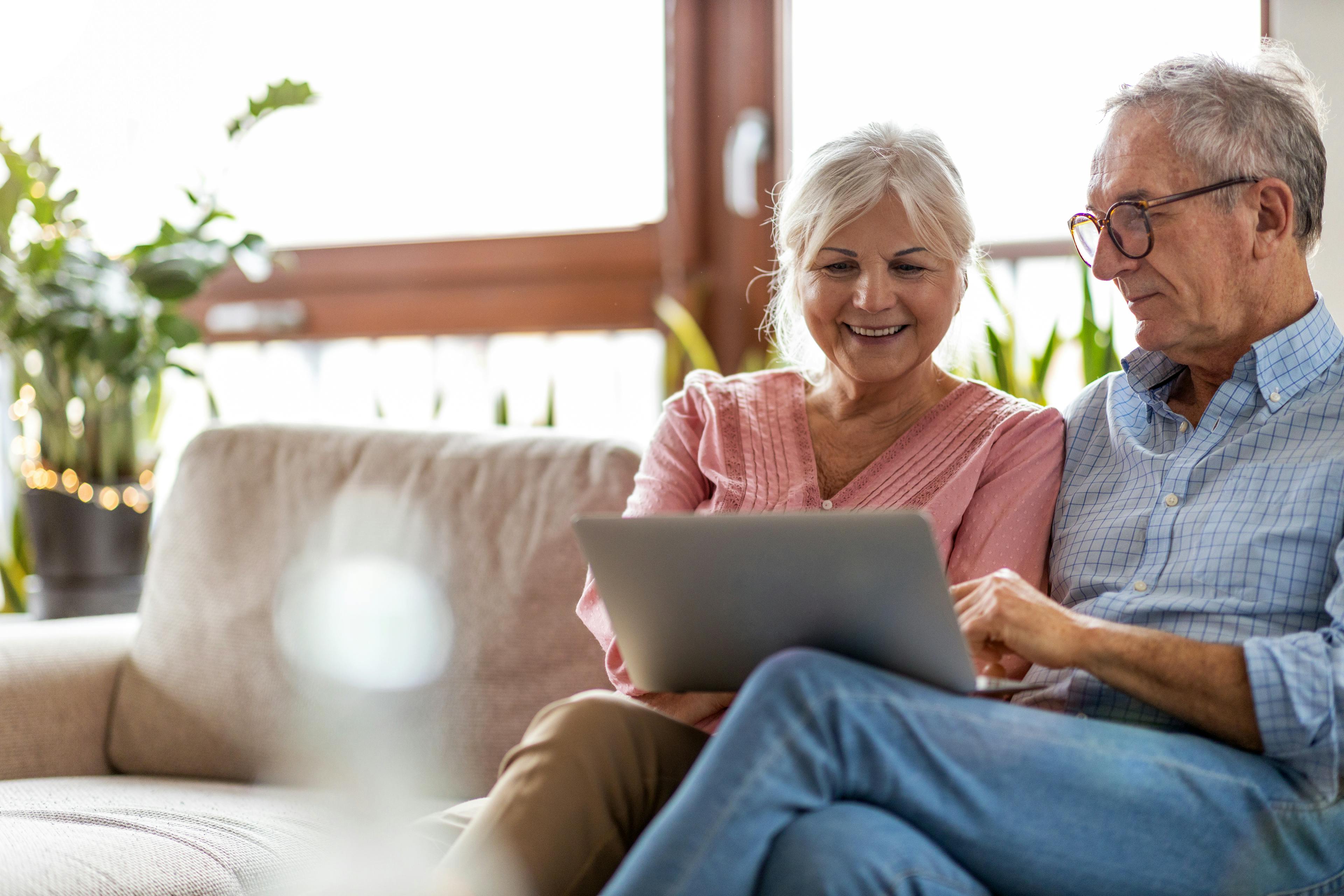 Mature couple using a laptop while relaxing at home.